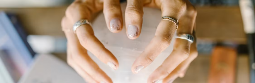 Ringed hands holding a clear crystal sphere symbolizing mediumship and spiritual healing practice.